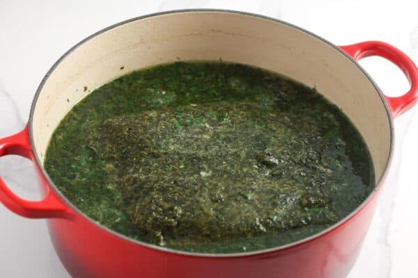 molokhia leaves cooking in broth in a dutch oven.
