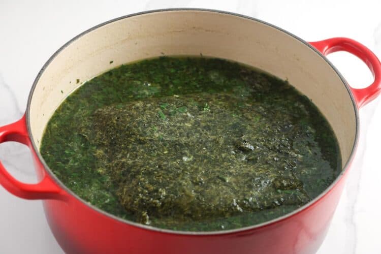 molokhia leaves cooking in broth in a dutch oven.