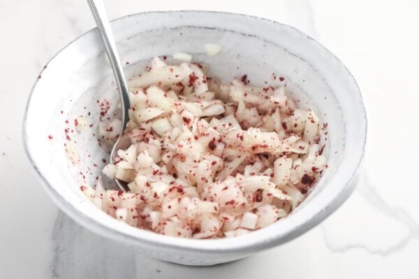onion mixed with sumac and lemon in a small bowl.