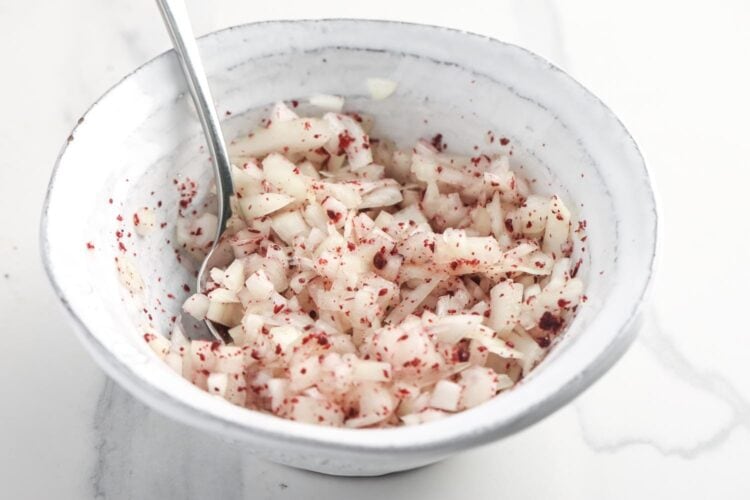 onion mixed with sumac and lemon in a small bowl.