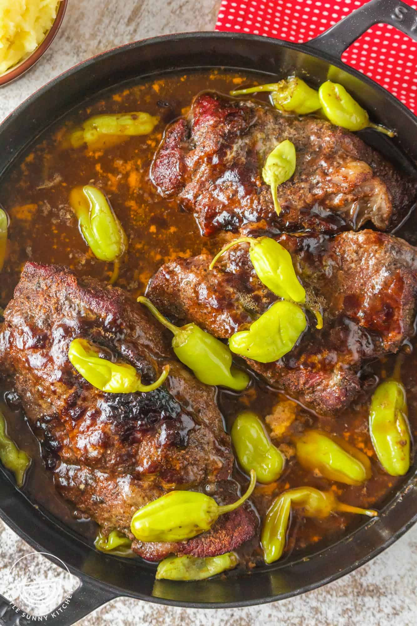 overhead view of smoked mississippi pot roast with peppers and gravy.
