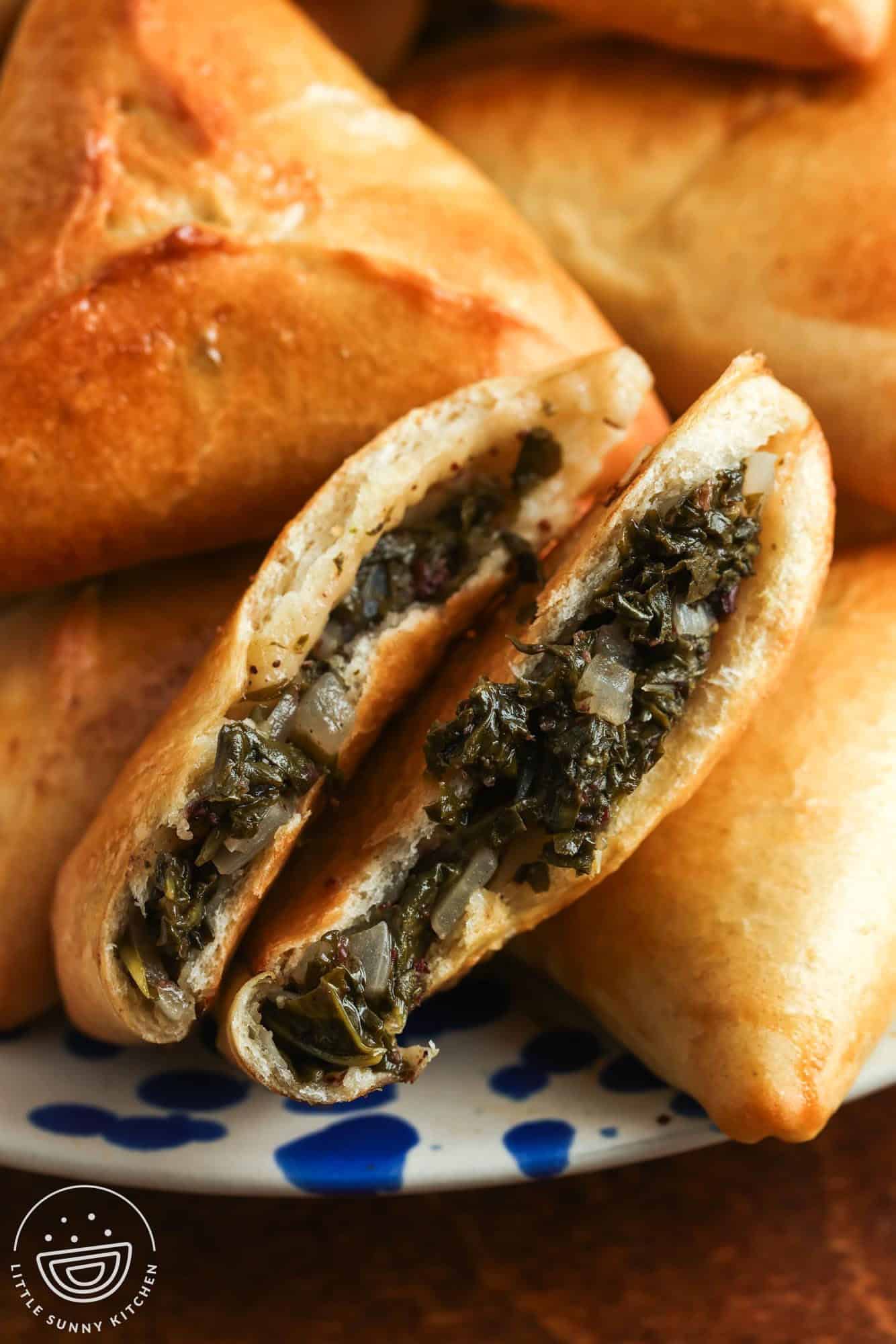 a spinach fatayer hand pie broken in half to show the filling and the light texture of the dough.
