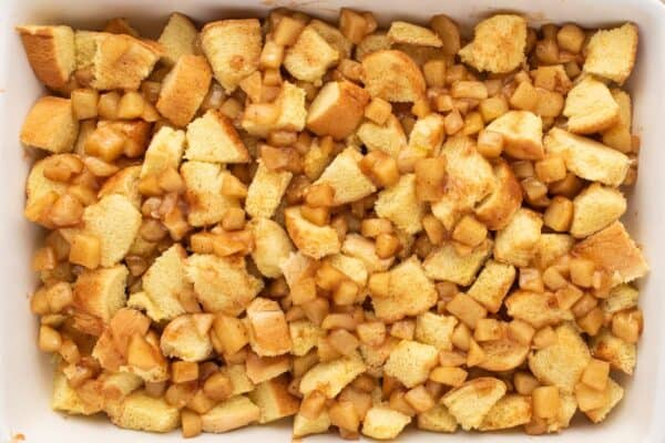 cubes of brioche with cooked apples, arranged in a 9x13 baking dish.