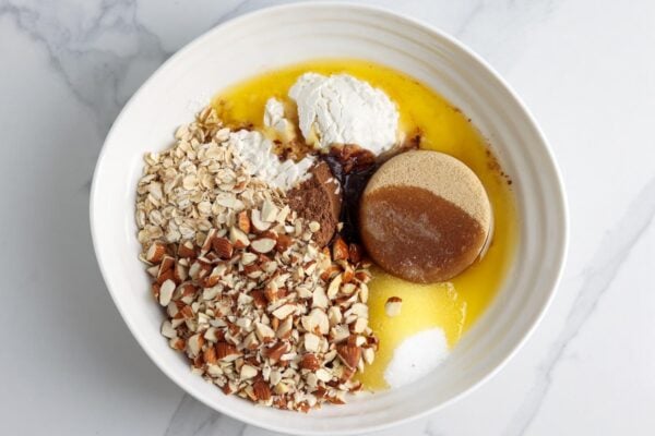 chopped almonds, oats, brown sugar, and butter in a white ceramic bowl.