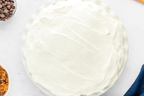 Whipped topping layer smoothed over the chocolate pudding in the pie dish.