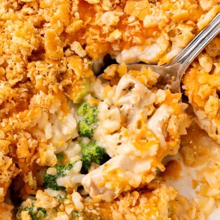 closeup of a creamy chicken broccoli rice casserole. a spoon is lifting up a serving.