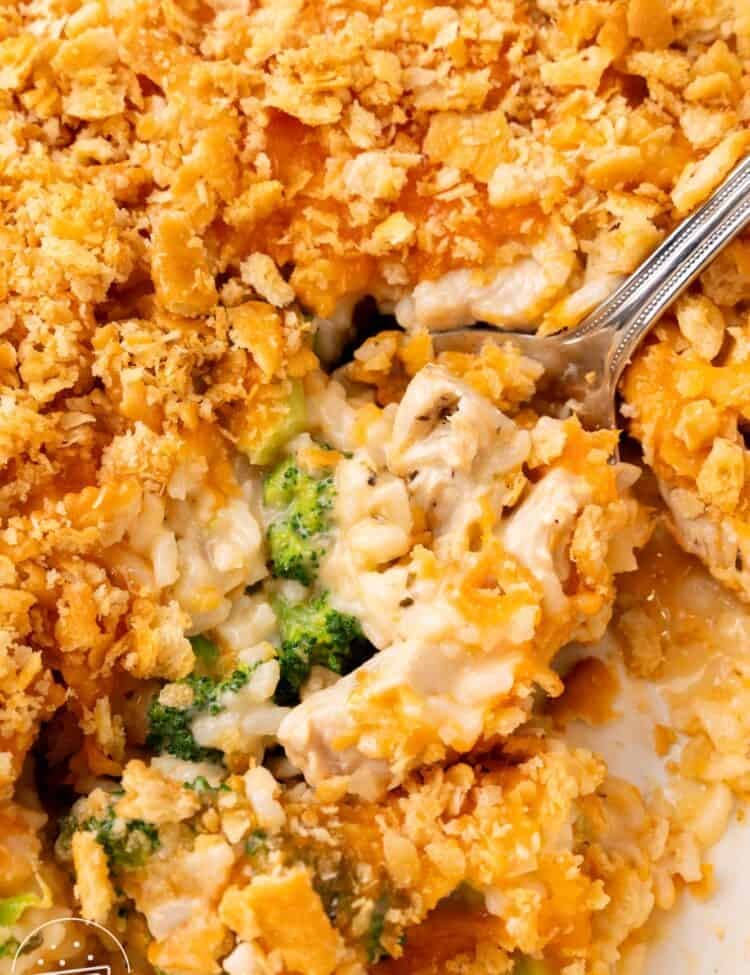 closeup of a creamy chicken broccoli rice casserole. a spoon is lifting up a serving.