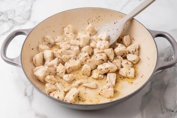 cooked cubes of chicken breast in a skillet.