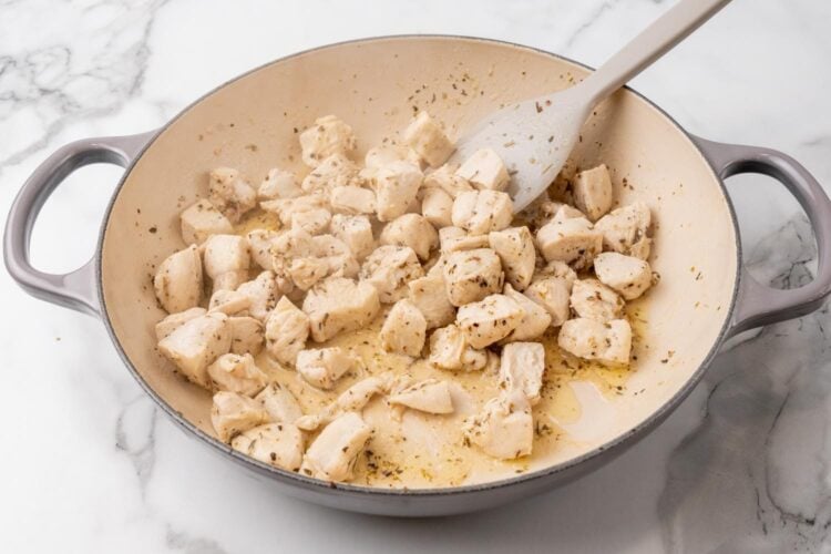 cooked cubes of chicken breast in a skillet.