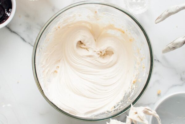 The cheesecake filling fully mixed, smooth and fluffy, in a glass bowl.