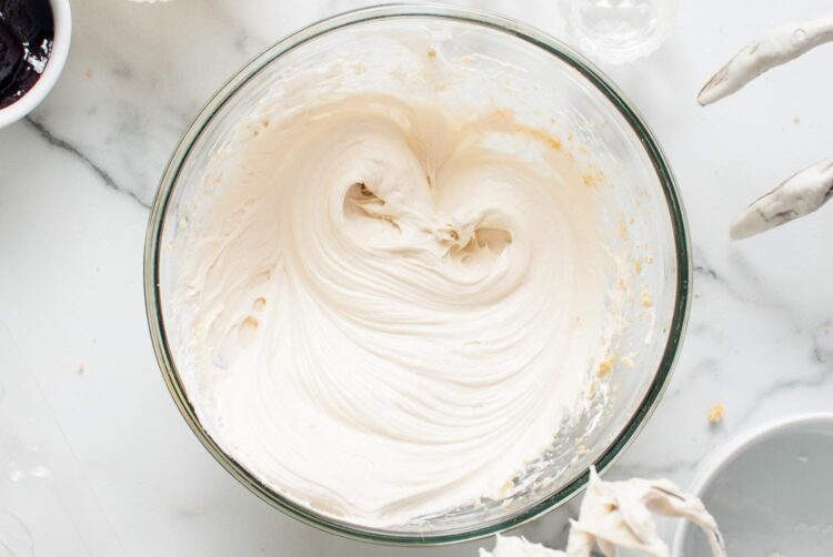 The cheesecake filling fully mixed, smooth and fluffy, in a glass bowl.