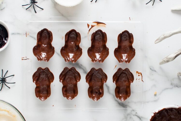 Frog molds fully coated with chocolate, smoothed and ready for chilling before unmolding.