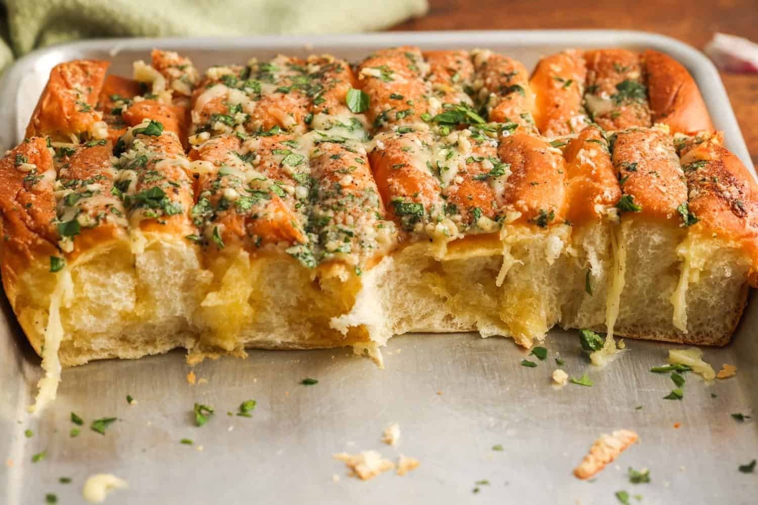 Baked Hawaiian roll garlic bread cut open to show fluffy texture with melted cheese and garlic butter.