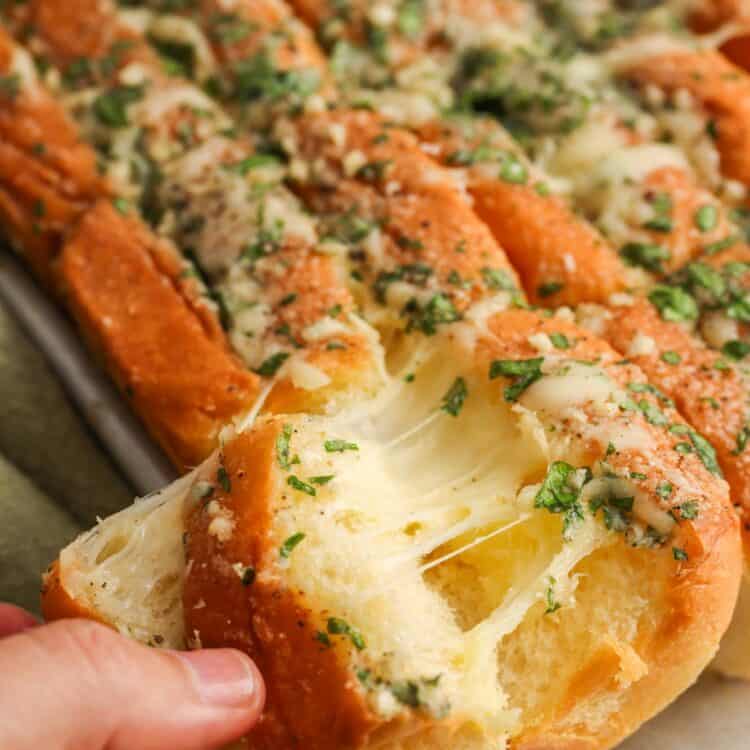 Gooey cheese pull from Hawaiian roll garlic bread with garlic butter and herbs.