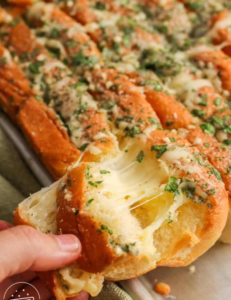 Gooey cheese pull from Hawaiian roll garlic bread with garlic butter and herbs.