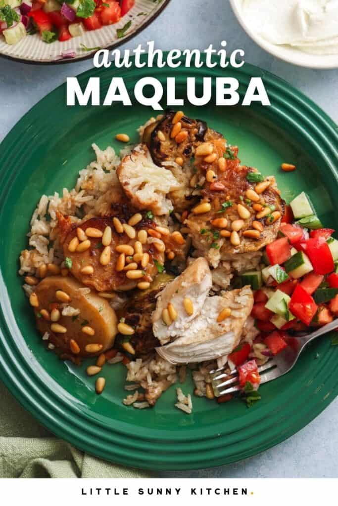 a dark green plate with a serving of maqluba with chicken and potato slices. On the side is cucumber and tomato salad.