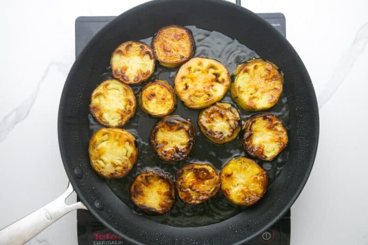 slices of eggplant fried in oil in a nonstick pan.