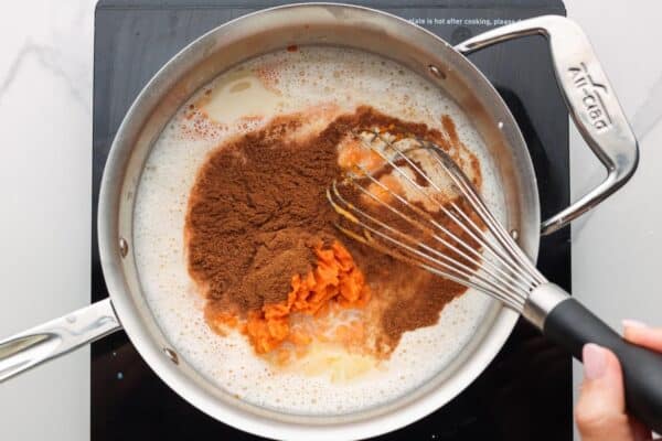 pumpkin puree and spices added to pudding base in a metal saucepan, stirred with a wire whisk.