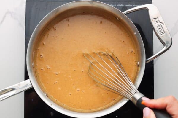 Thickened pumpkin pudding on the stove, stirred with a whisk.