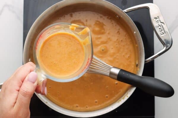 tempered egg mixture added to the pan of pumpkin pudding.