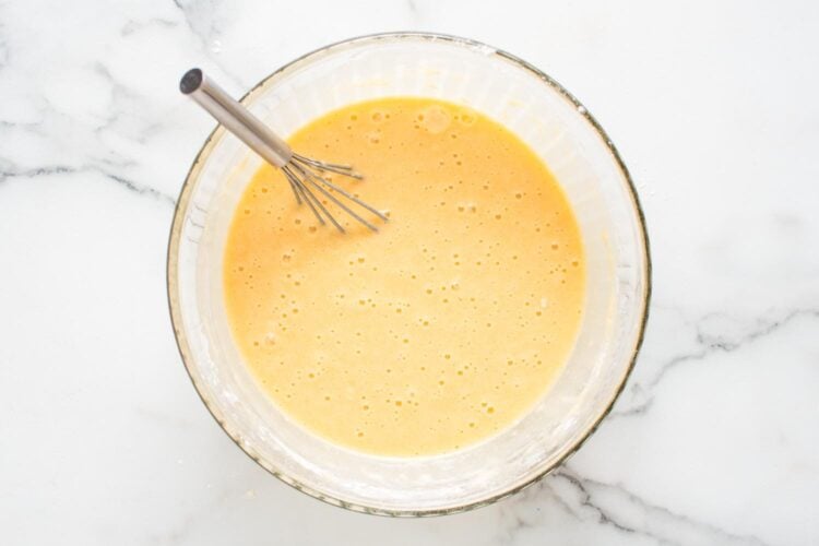 vanilla cupcake batter in a glass bowl with a whisk.