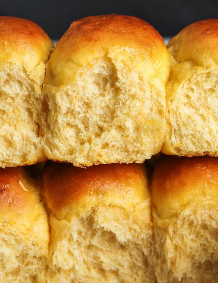 two rows of sweet potato dinner rolls stacked on top of each other. The rolls viewed from the side are fluffy and airy.