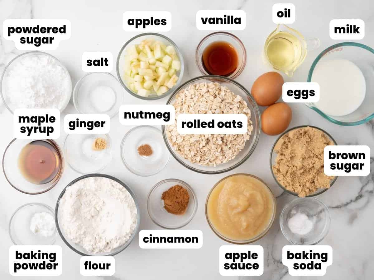 The ingredients needed to bake homemade apple oat muffins, measured into small glass bowls and arranged on a marble counter.