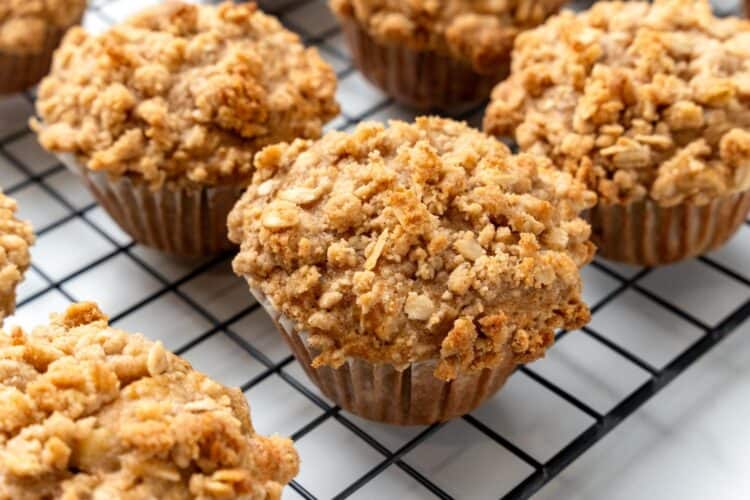 closeup of baked apple oat muffins with crumb topping, cooling on a wire rack.