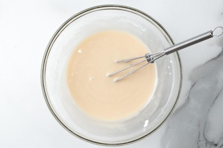 icing mixed in a small glass bowl with a whisk.