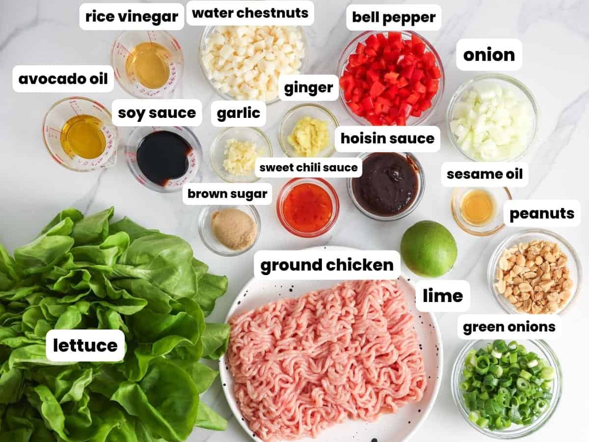 Ingredients for homemade Asian chicken lettuce wraps, including ground chicken, butter lettuce, Asian sauces, water chestnuts, bell peppers, and peanuts.
