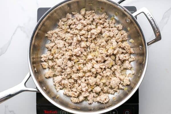 ground chicken cooked with onions in a skillet, viewed from overhead.
