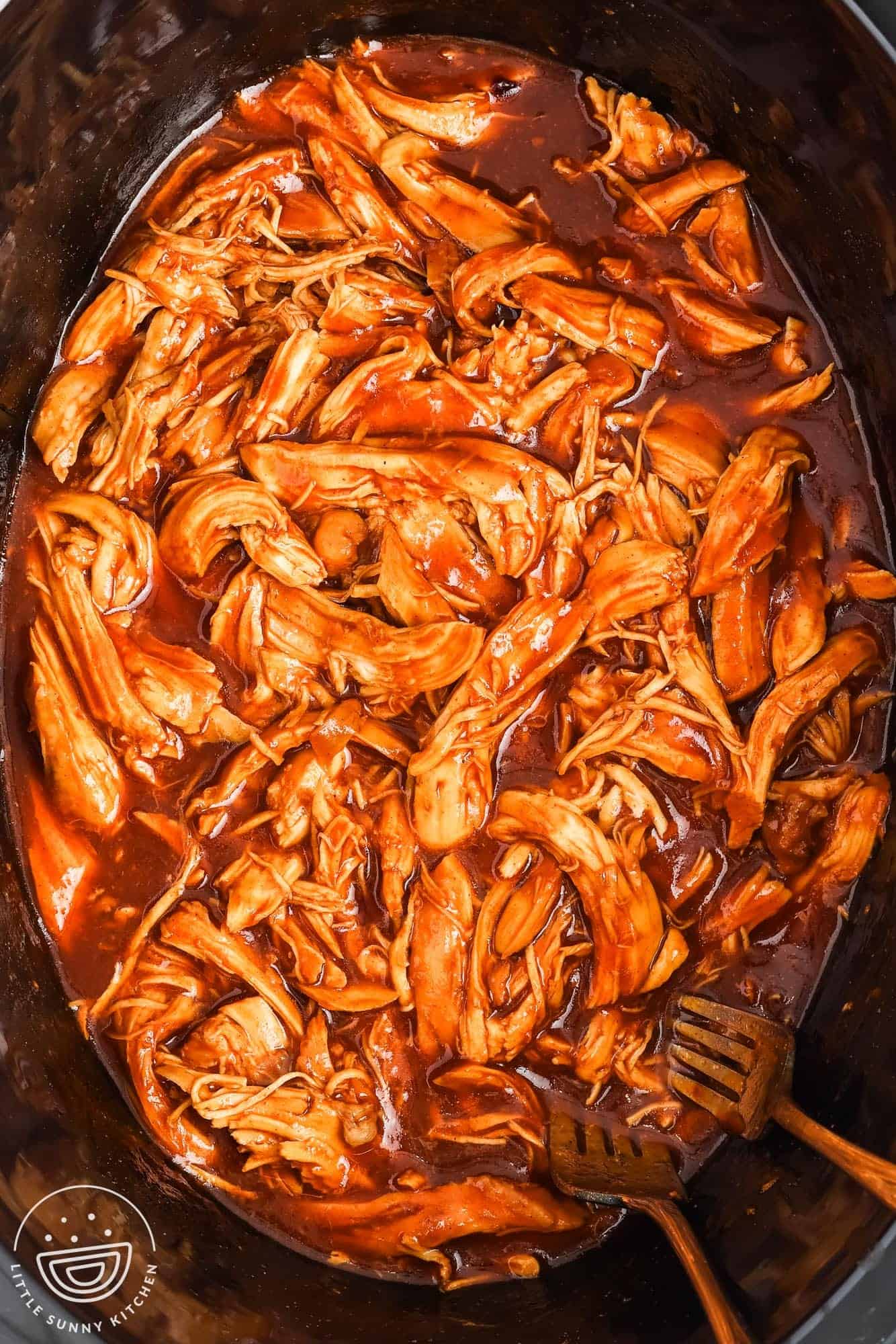bbq crockpot pulled chicken with two forks in a black pot.