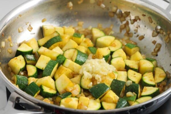 diced zucchini and garlic added to a skillet of sauteed onions.