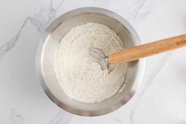 flour, baking soda, yeast, and salt, combined in a metal bowl with a bread whisk.