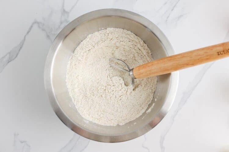 flour, baking soda, yeast, and salt, combined in a metal bowl with a bread whisk.