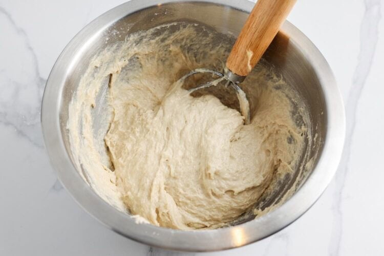 loose, shaggy dough for english muffin bread in a mixing bowl with a bread whisk.