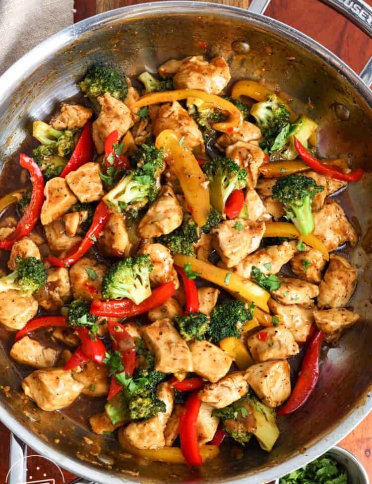 overhead view of a skillet holding hoisin chicken with broccoli and peppers.