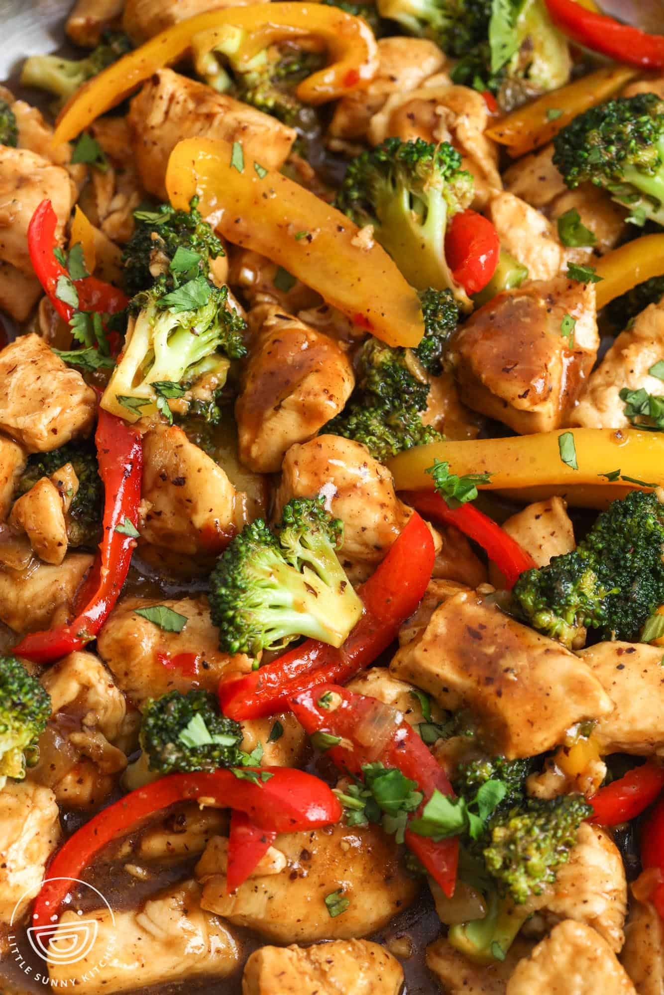closeup of hoisin chicken stir fry with red peppers and broccoli and bite sized pieces of chicken breast.