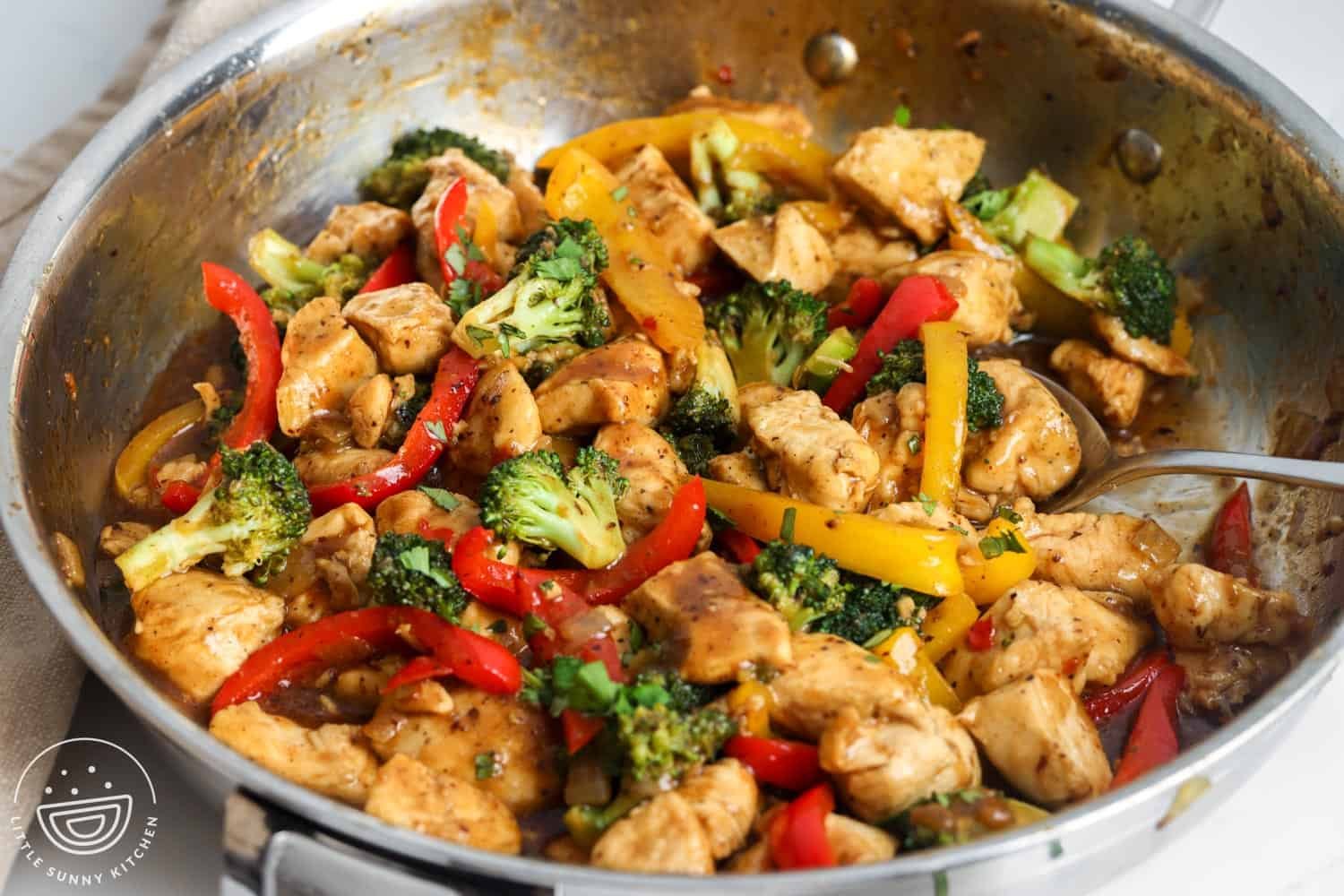 Hoisin Chicken with peppers and broccoli in a rich sauce, cooking in a skillet.