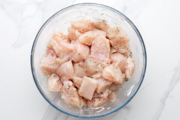 cubed chicken breast in a bowl, seasoned with salt and pepper and coated in cornstarch.