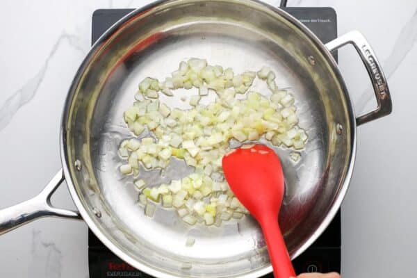 diced onions sauteed in oil in a stainless steel skillet.