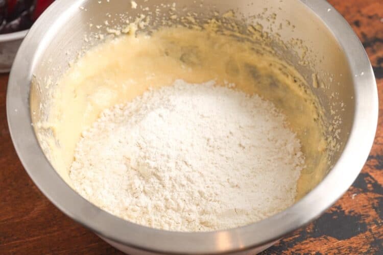 Flour mixture added to the creamed butter, sugar, and eggs in a stainless steel mixing bowl.