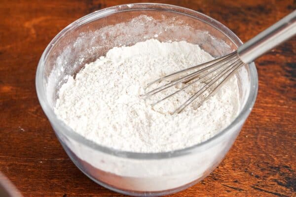 Overhead view of a bowl of flour and spices whisked together for pumpkin cookie dough.