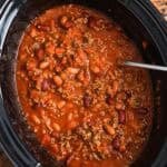 overhead view of beef chili in a black oval crockpot.