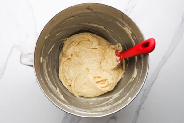 thick cake batter in a metal mixing bowl with a red spatula.