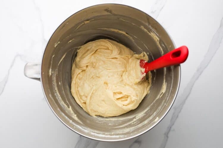 thick cake batter in a metal mixing bowl with a red spatula.