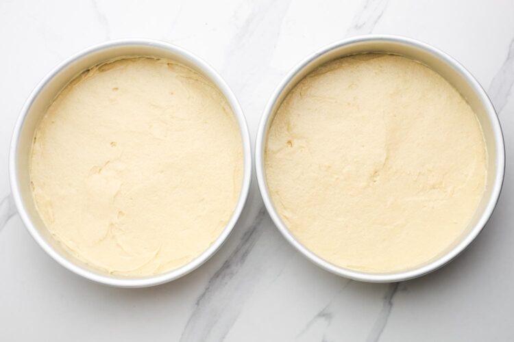 batter for victoria sponge cake spread evenly into two round metal cake pans.