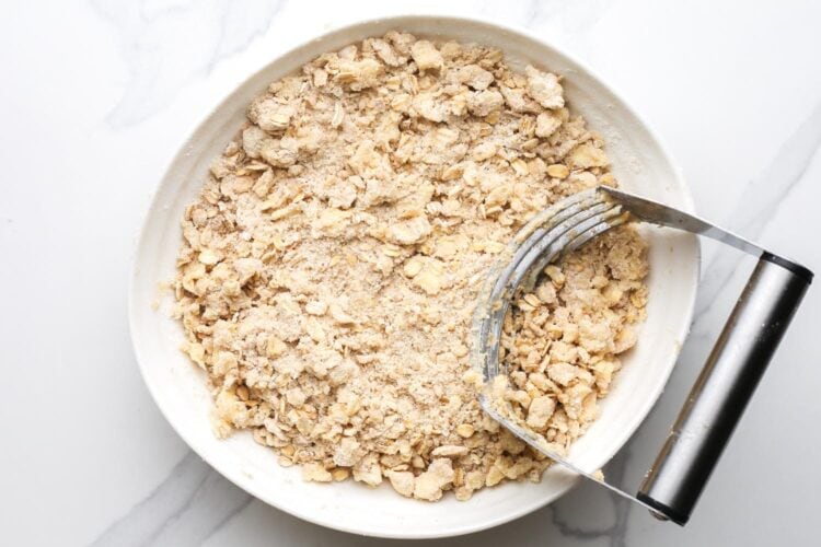 cold butter cut into flour and oats mixture with a pastry cutter to make the topping for apple crisp.
