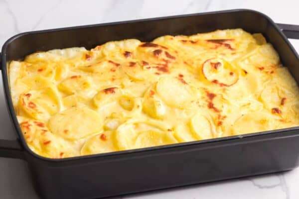 baked cheesy scalloped potatoes in a black baking dish.