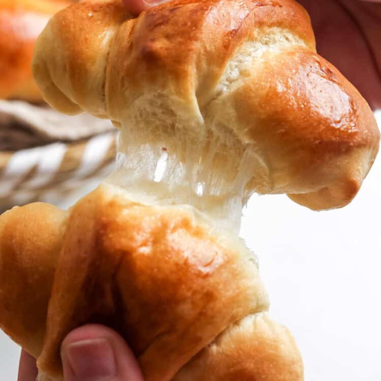 hands holding two crescent rolls, pulling them apart.
